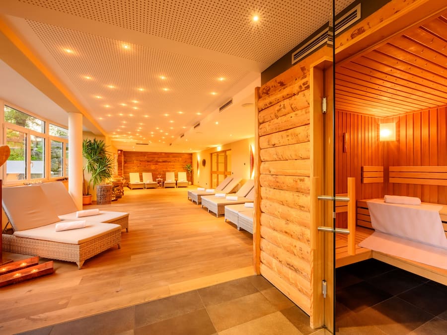 Ein Wellnessbereich mit Holzwänden, einem großen Fenster und einer Sitzecke mit Kissen.