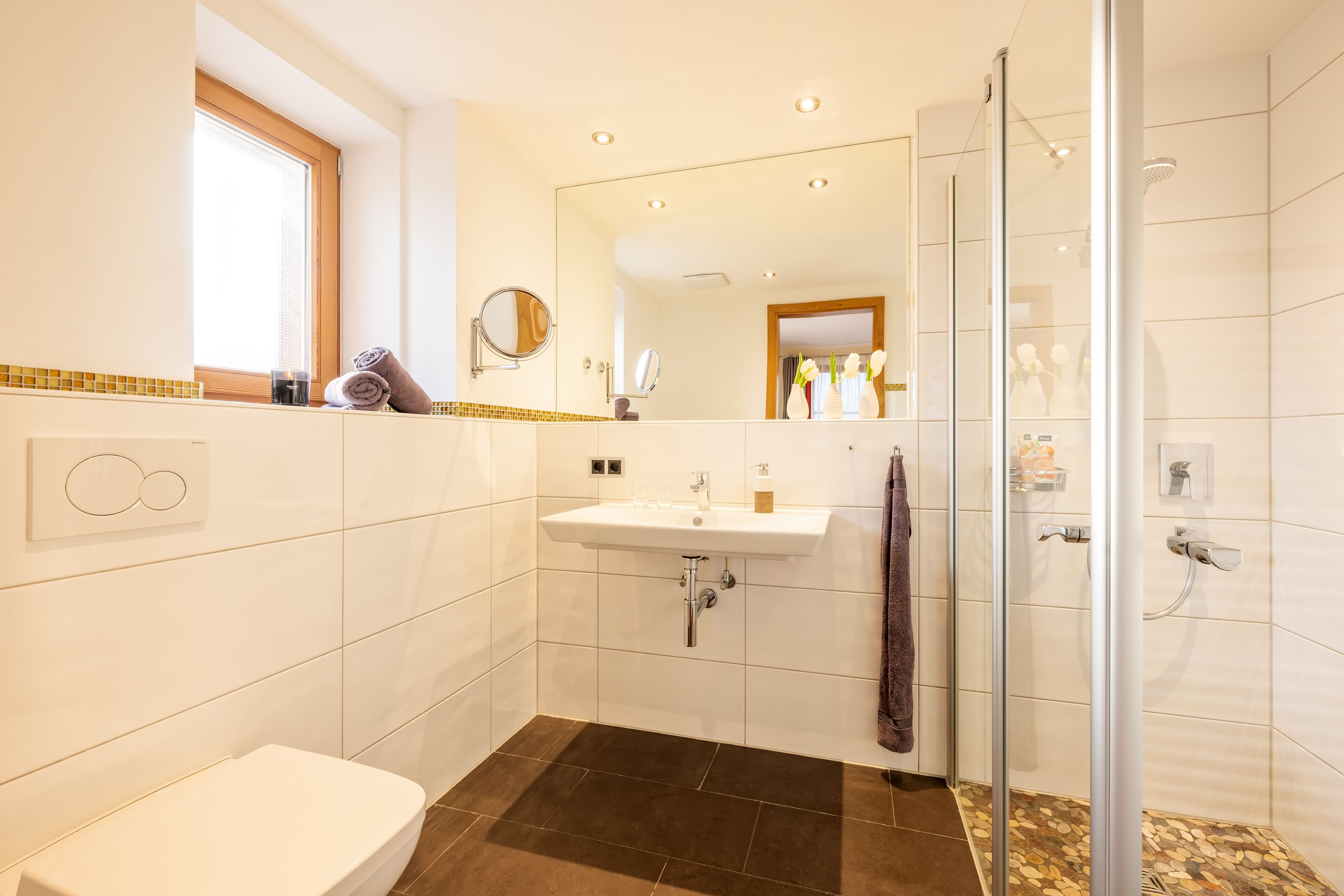 Un baño moderno con inodoro, lavamanos y ducha.