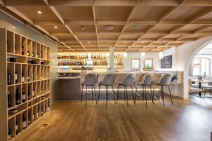 A bar area with wooden shelves, bar stools, and a counter.
