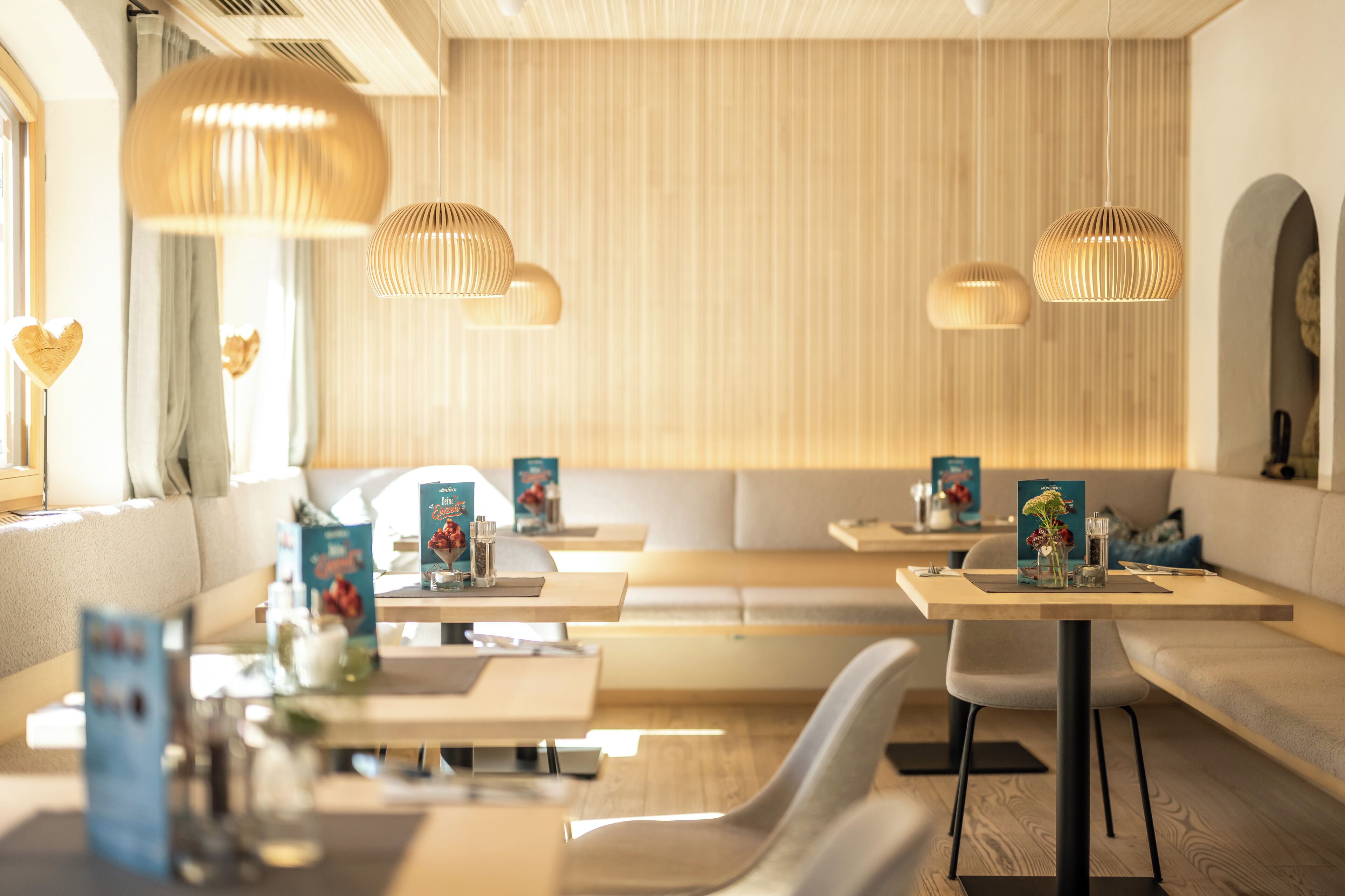 A modern restaurant with wooden accents, pendant lighting, and a cozy seating area.