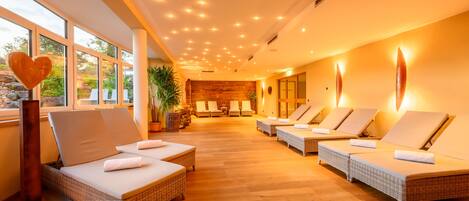 Zona de spa con sillones de mimbre, una decoración en forma de corazón y vistas al exterior a través de amplias ventanas.