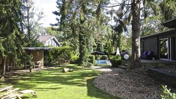 Ein Garten mit Schwimmbad, überdachter Terrasse und kleiner Gartenhütte.