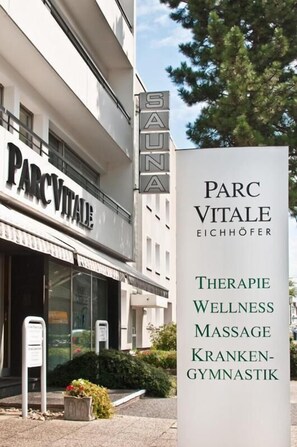 A building with a sign for 'PARC VITALE EICHHÖFER' and a list of services including therapy, wellness, massage, and sports medicine.