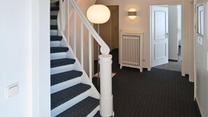 Een trap met een witte leuning en blauw beklede treden die uitkomen op een plateau.