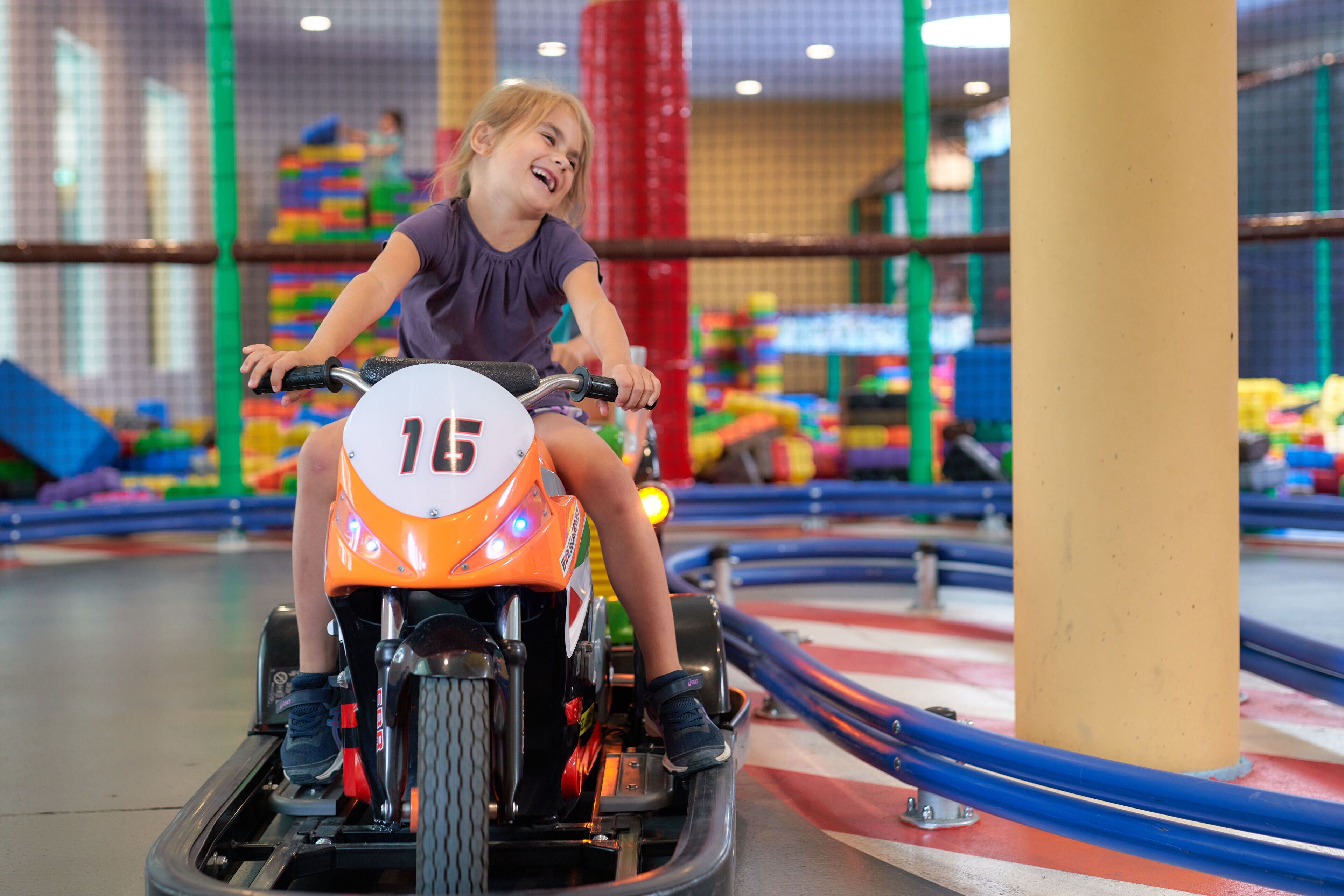 A child riding a go-kart with the number 15 on it.
