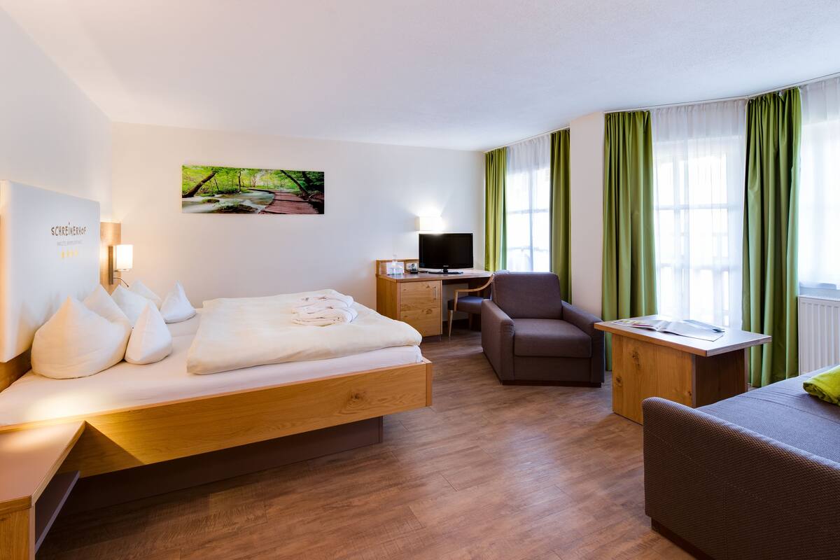 Une chambre d’hôtel avec un lit, un bureau, une chaise et un téléviseur.