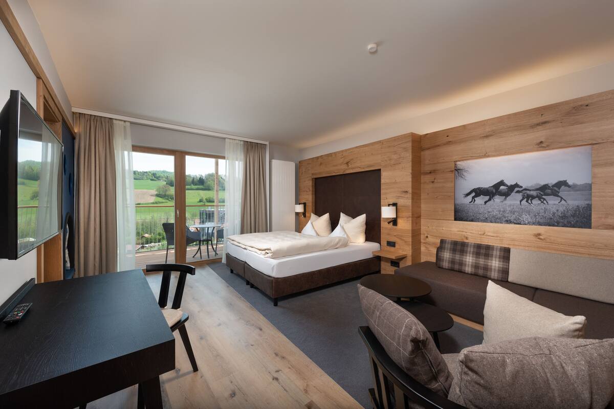 Une chambre d’hôtel moderne avec un grand lit, un bureau, un canapé et un tableau au mur.