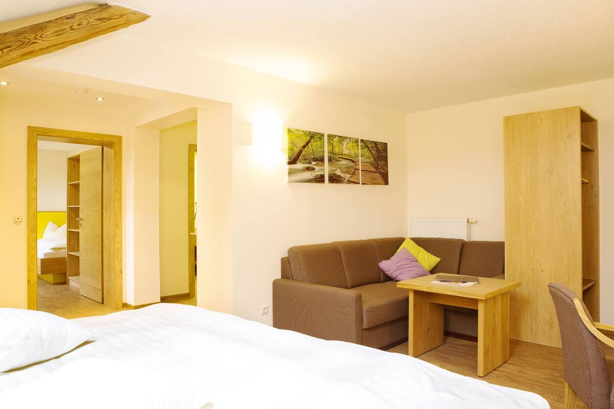 Une chambre à coucher avec un lit, un bureau en bois, un canapé marron et une armoire en bois.