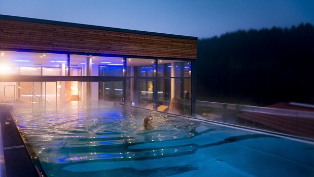 A modern building with a glass exterior and a pool area.