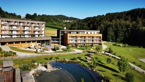 A modern hotel with multiple floors, outdoor swimming pool, and a scenic hillside view.