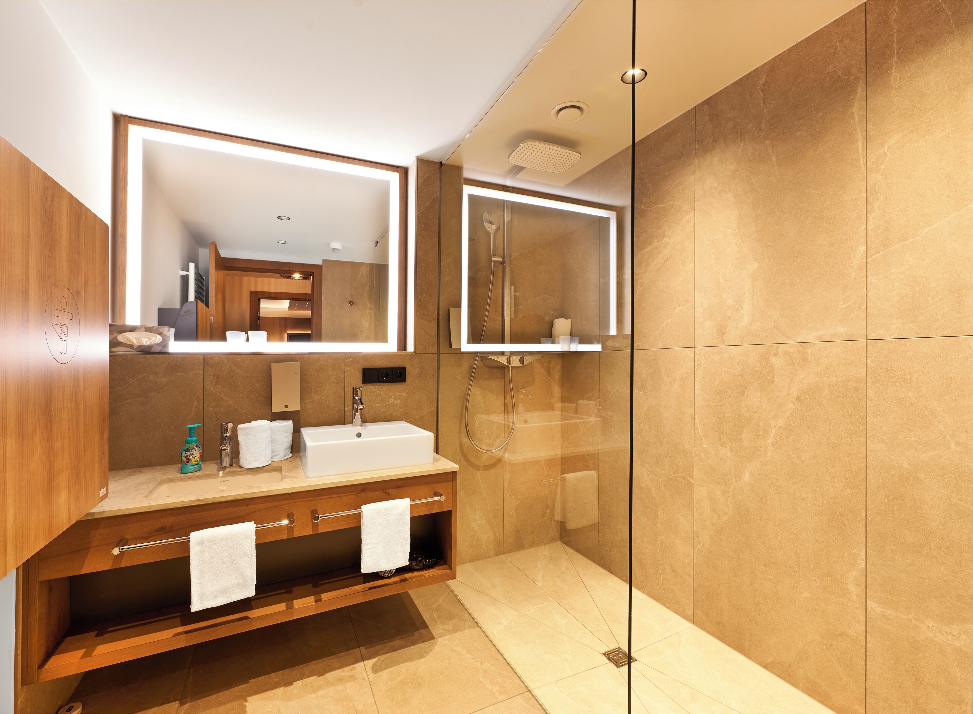Een moderne badkamer met een houten wastafel, een grote spiegel en een douche met glazen wanden.