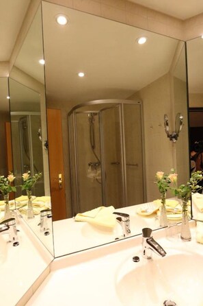 Une salle de bain moderne avec un grand miroir, un lavabo et une douche.