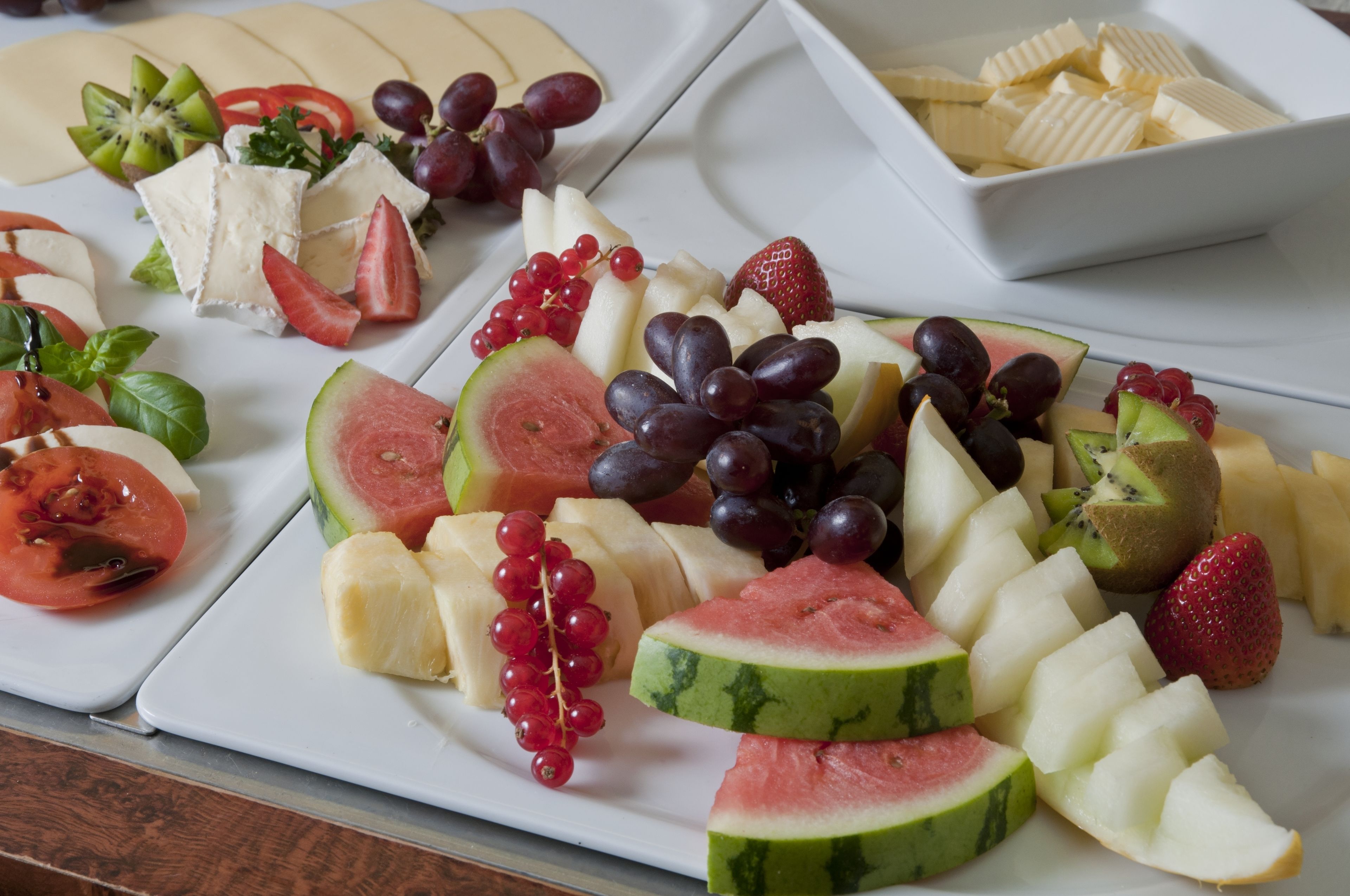 Eine Auswahl an Obst und Käse auf einem weißen Teller.