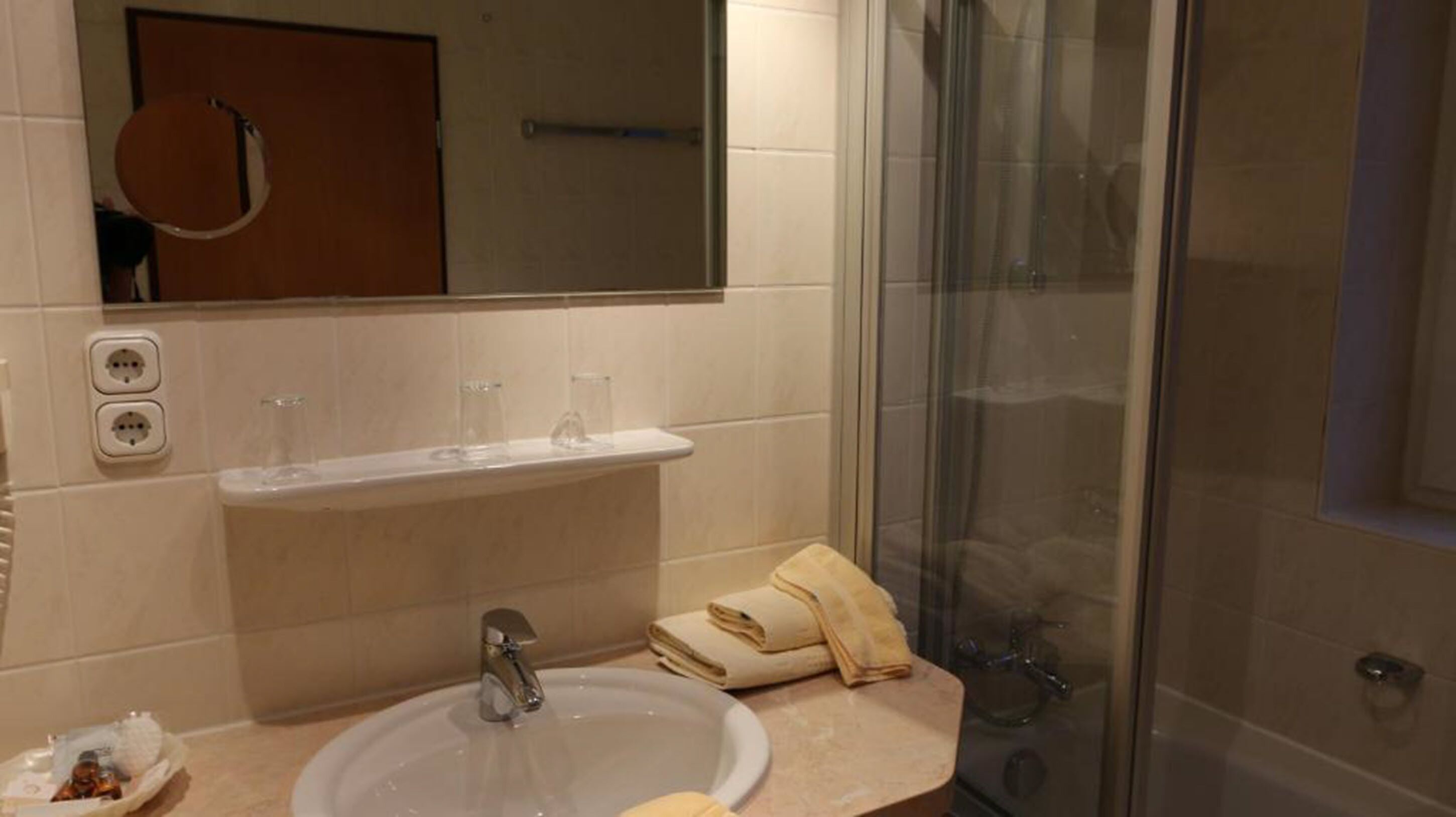 Une salle de bain équipée d’un lavabo, d’un miroir et d’une douche à parois en verre.