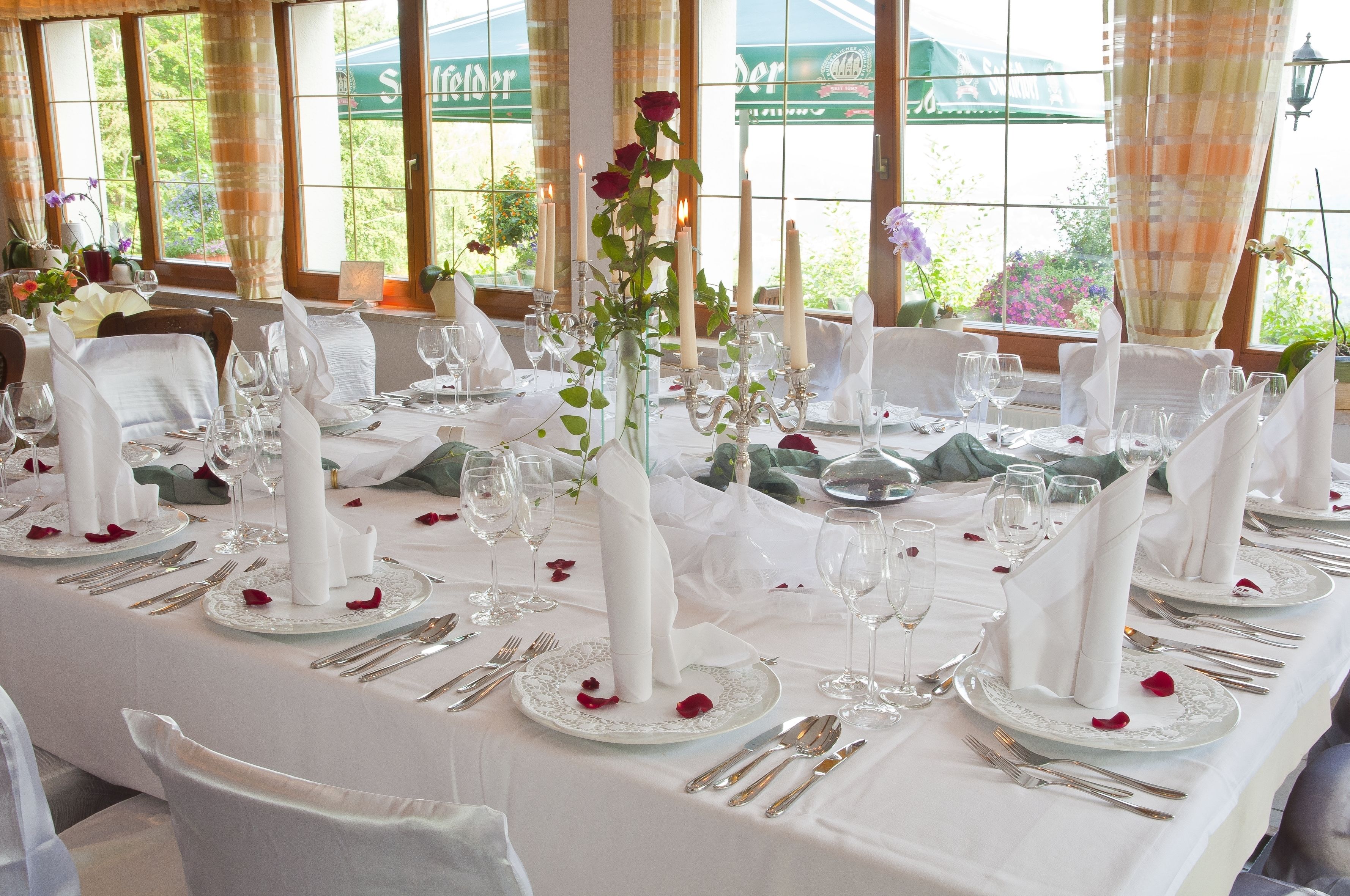 A banquet table set for a formal event with white tablecloths, silverware, and candle centerpieces.