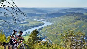 Zwei Radfahrer auf einem Mountainbike-Weg, im Hintergrund ein Fluss und eine Treterrasse mit Feldern.