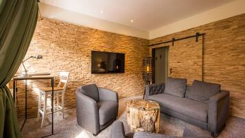 Ein modernes Wohnzimmer mit Ziegelwand, flachbildfernseher über einem Kamin und einer Sitzecke mit Sofa und Sesseln.
