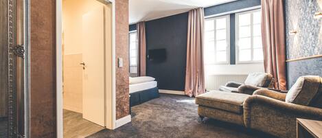 Una habitación moderna con un espejo grande, un sofá, una cama y un televisor.
