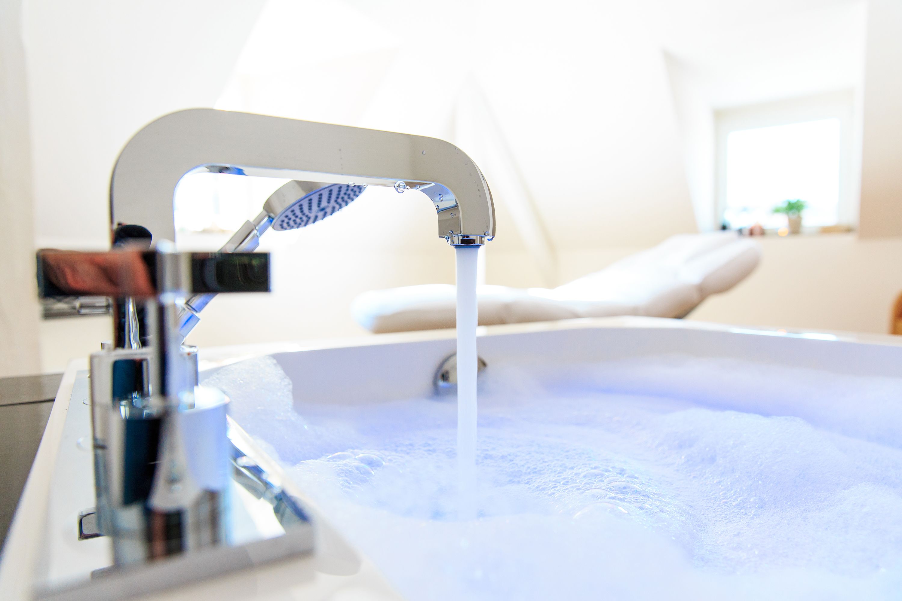 A bathroom with a bathtub, a faucet, and a window in the background.
