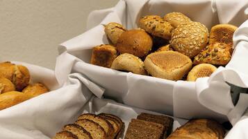 A basket of various breads and rolls, including seeded and sliced varieties.