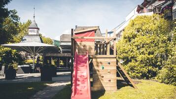 Explore the hotel's playground area, featuring a climbing structure with a slide and a shaded gazebo.