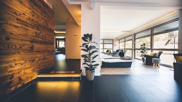 A modern lobby with a wooden wall, a reception desk, and a seating area with a large window.