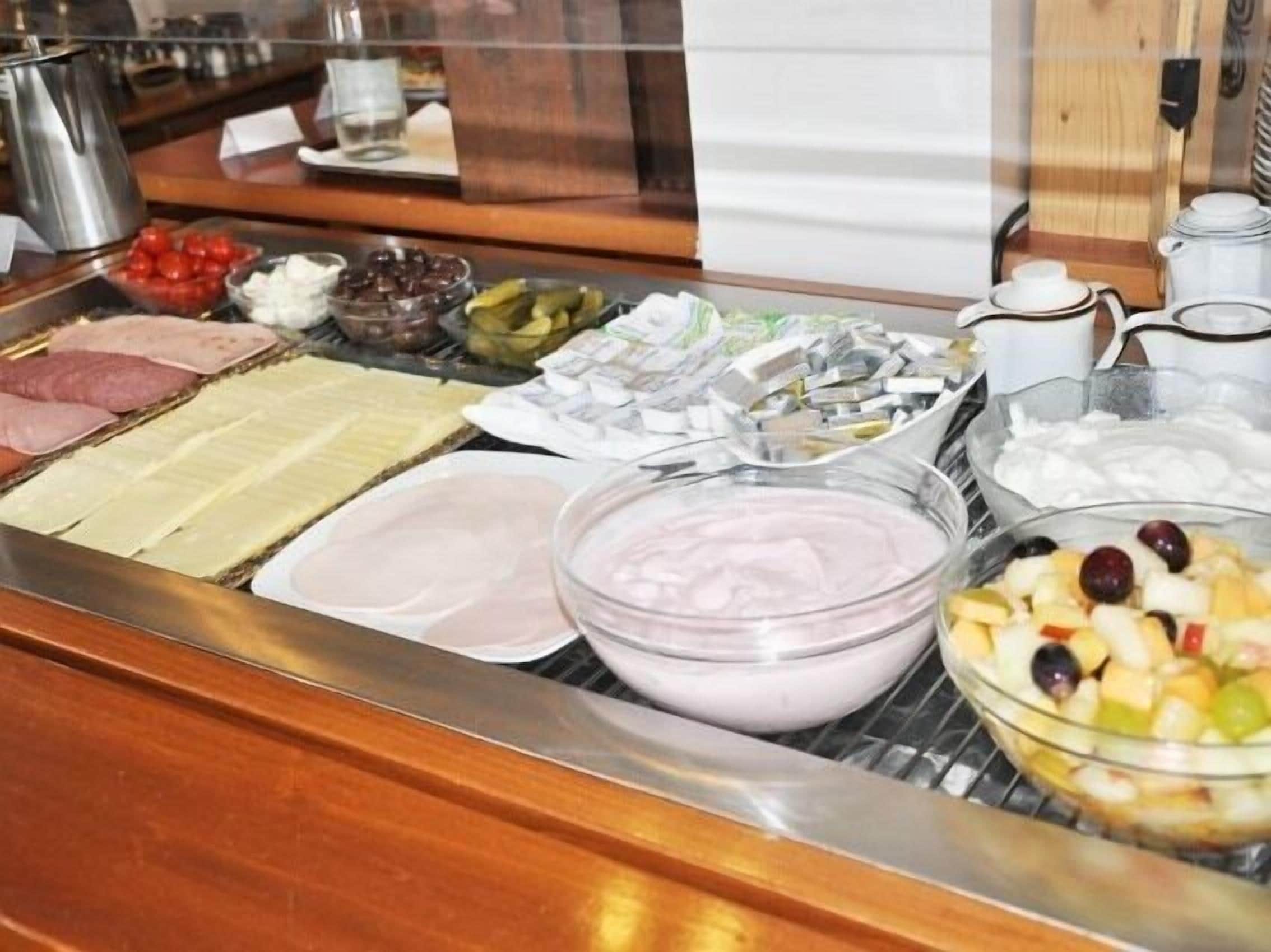 Un bufé con diferentes opciones de comida, incluyendo carnes, quesos y frutas.