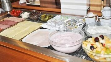 Un bufé con diferentes opciones de comida, incluyendo carnes, quesos y frutas.