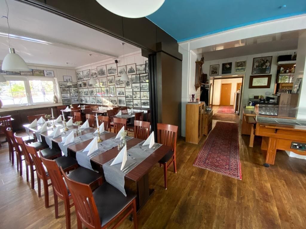 A dining area with wooden tables and chairs, a large window with artwork, and a view of the outside.