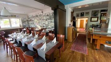 A dining area with wooden tables and chairs, a large window with artwork, and a view of the outside.