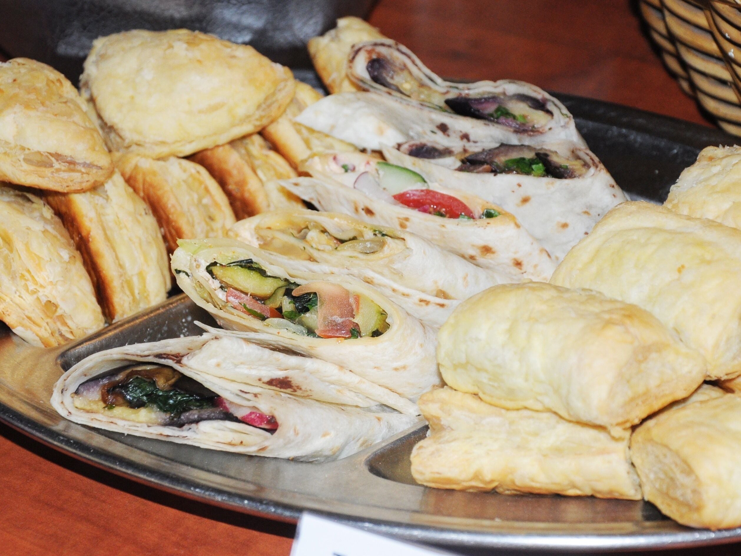 A tray of food including wraps and pastries.