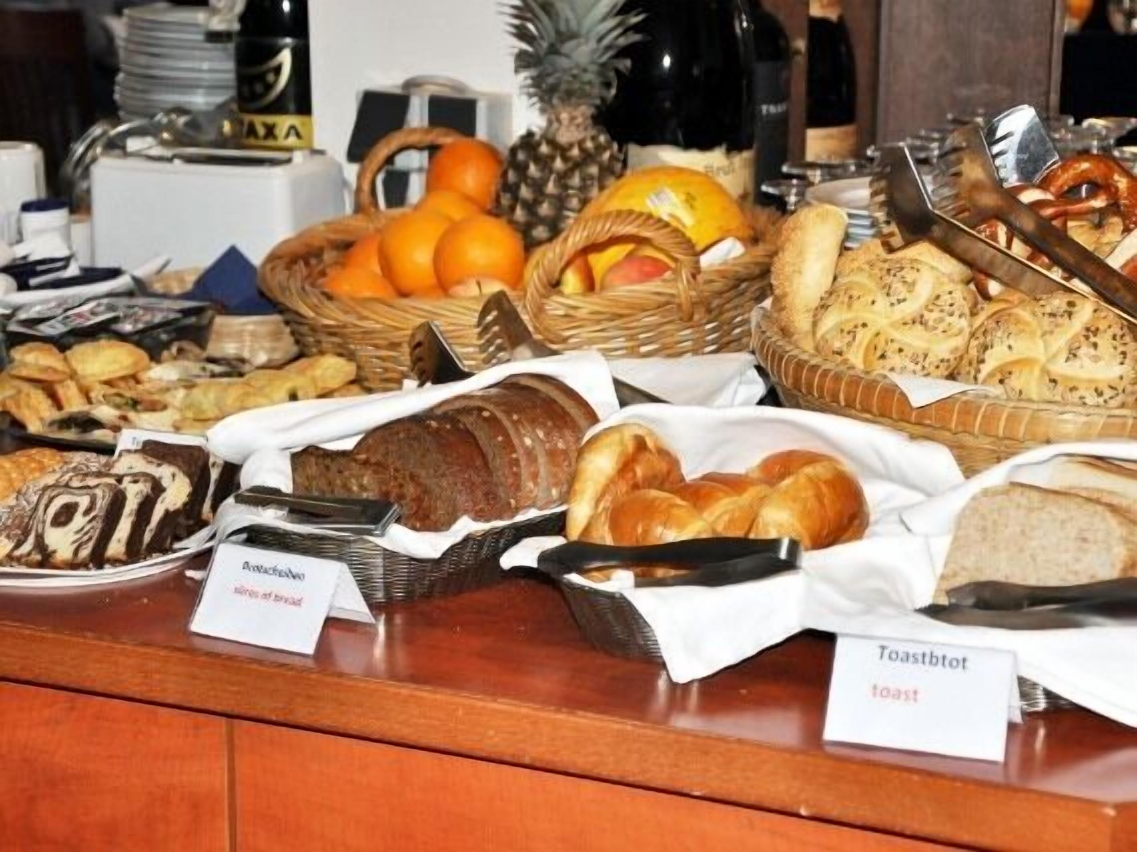 A buffet with various breads, pastries, and fruits.