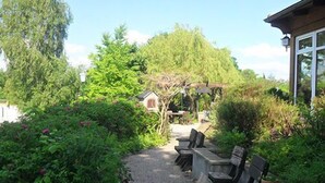 A gravel path leading to a seating area with benches and a small birdhouse. - Landhotel Peters (Wustrow)