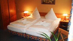 A hotel room with a double bed, two bedside lamps, a wooden wardrobe, and a painting on the wall. - Landhotel Peters (Wustrow)