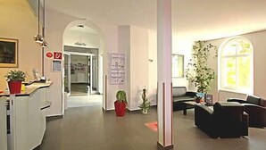 Un espacio habitable amplio con sofá, una mesa de centro y una mesa de comedor. Hay una planta en maceta y una ventana que proporciona luz natural.