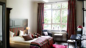 A hotel room with a bed, a desk, a chair, and a window with curtains.