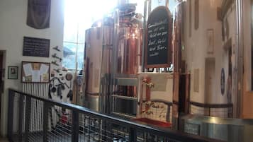 A brewery with stainless steel brewing equipment, a chalkboard with brewing instructions, and a view of the outside through a window.