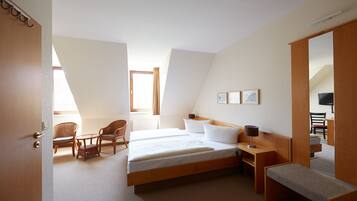 Una habitación de hotel con una cama grande, dos sillas, una mesita, un banco y un televisor.