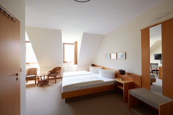 A hotel room with a large bed, two chairs, a small table, a bench, and a TV. - Hotel Garni Zum Eichwerder (Templin)
