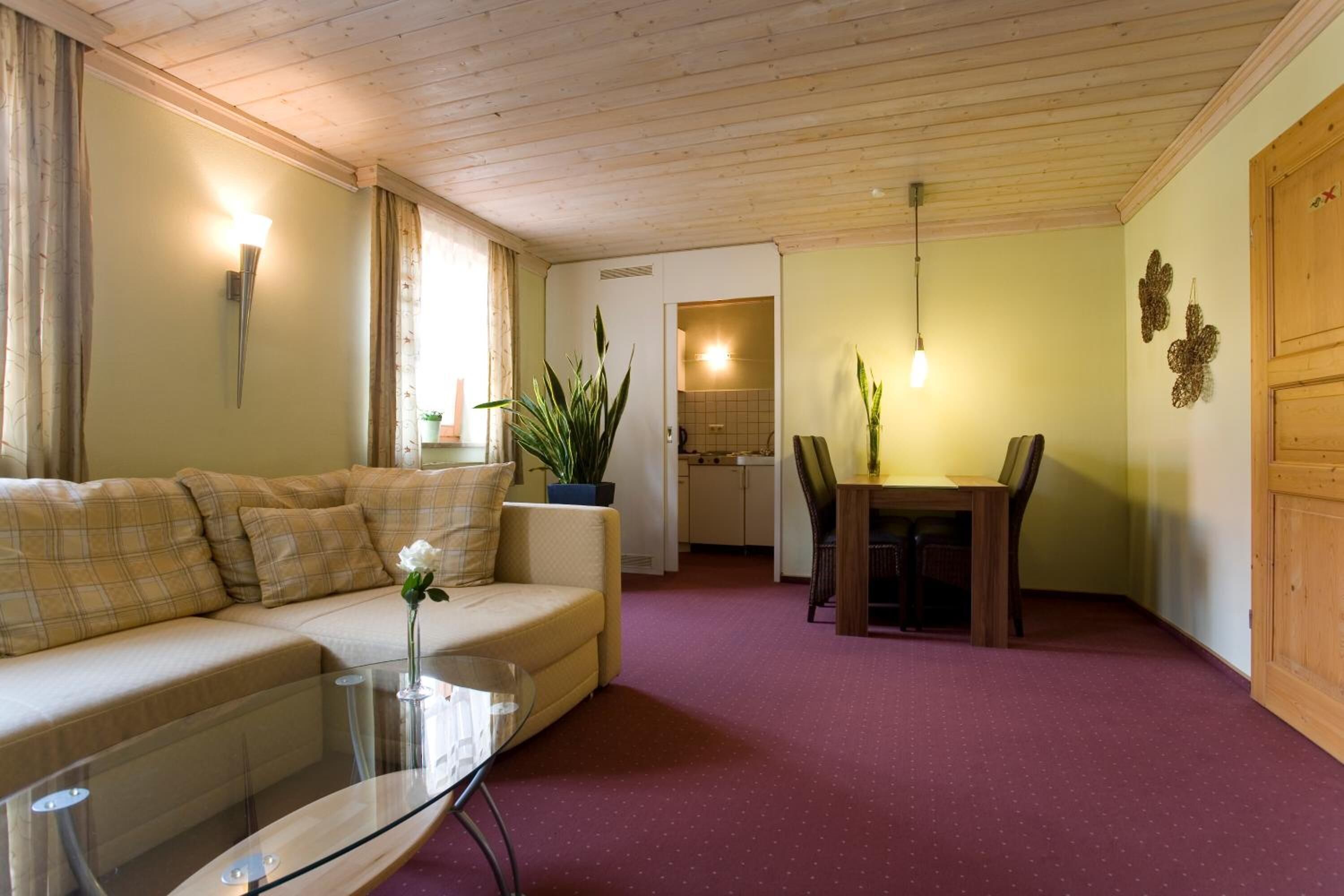 Ein gemütliches Wohnzimmer mit einer Couch, einem Glastisch und einem Essbereich mit Tisch und Stühlen.