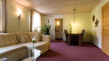 Ein gemütliches Wohnzimmer mit einer Couch, einem Glastisch und einem Essbereich mit Tisch und Stühlen.