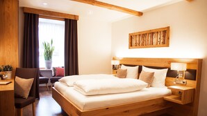 A modern hotel room with a wooden bed, a desk, and a chair. - Pension Sommer (Waldsassen)