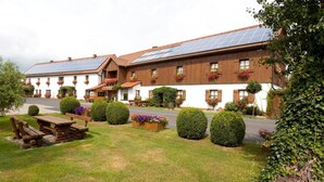 A building with a white facade, wooden shutters, and solar panels on the roof. - Pension Sommer (Waldsassen)