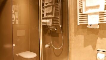Un bagno moderno con cabina doccia in vetro, un water e un portasciugamani.