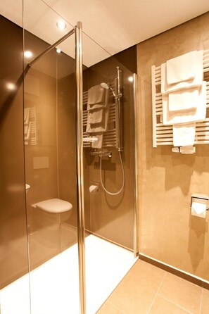 A modern bathroom with a glass-enclosed shower, a toilet, and a towel rack. - Pension Sommer (Waldsassen)