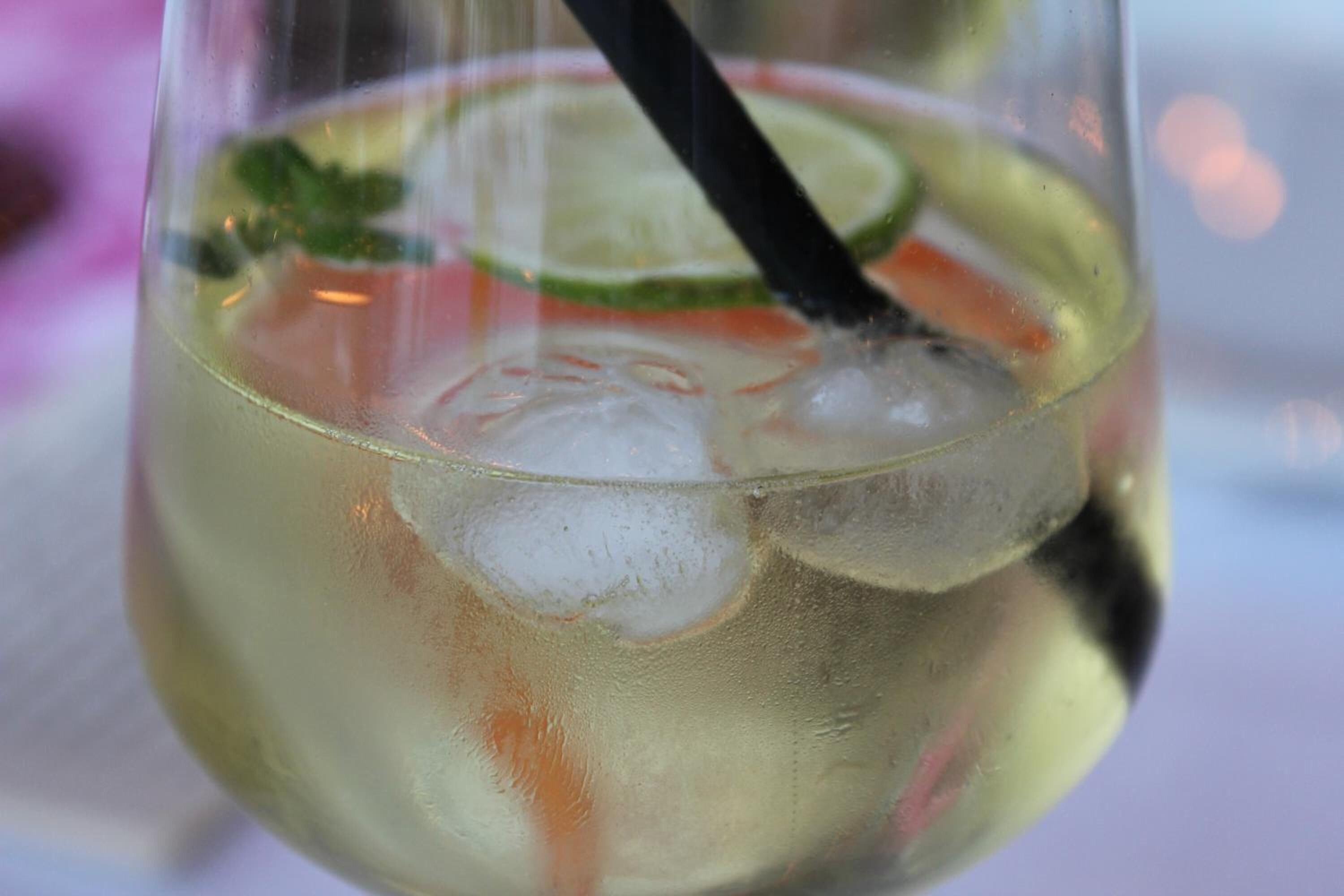 Ein Glas mit einem Getränk, Eiswürfeln und einer Limettenscheibe.