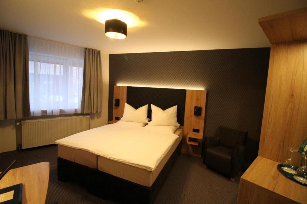 Une chambre d’hôtel avec un grand lit, un bureau, une chaise et une fenêtre avec des rideaux.