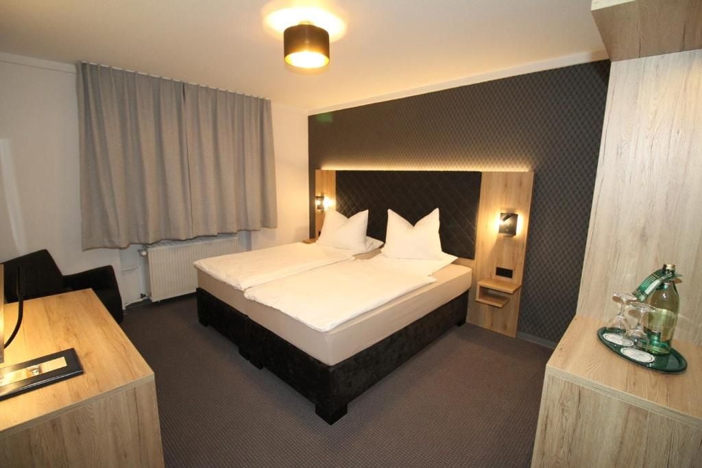 A hotel room with a double bed, bedside tables, a desk, and a chair.