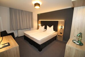 A hotel room with a double bed, bedside tables, a desk, and a chair. - Gasthaus Bonneberger Hof (Vlotho)
