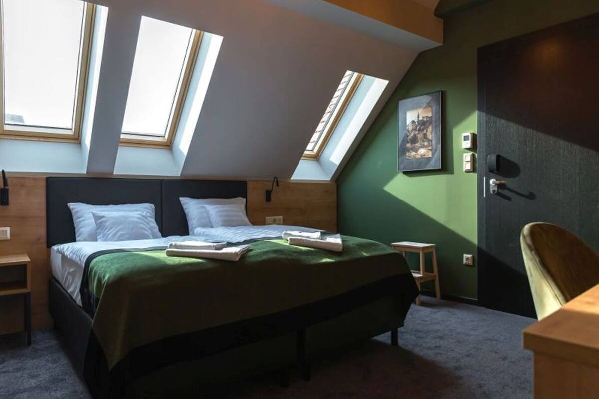 A bedroom with a bed, skylights, a desk, and a chair.